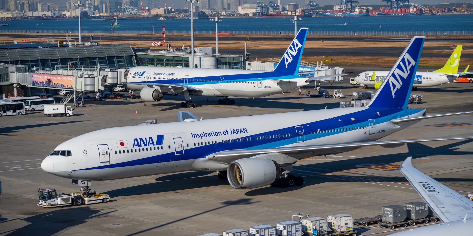 An ANA aircraft on the tarmac with Tokyo Bay and the Tokyo skyline in the background